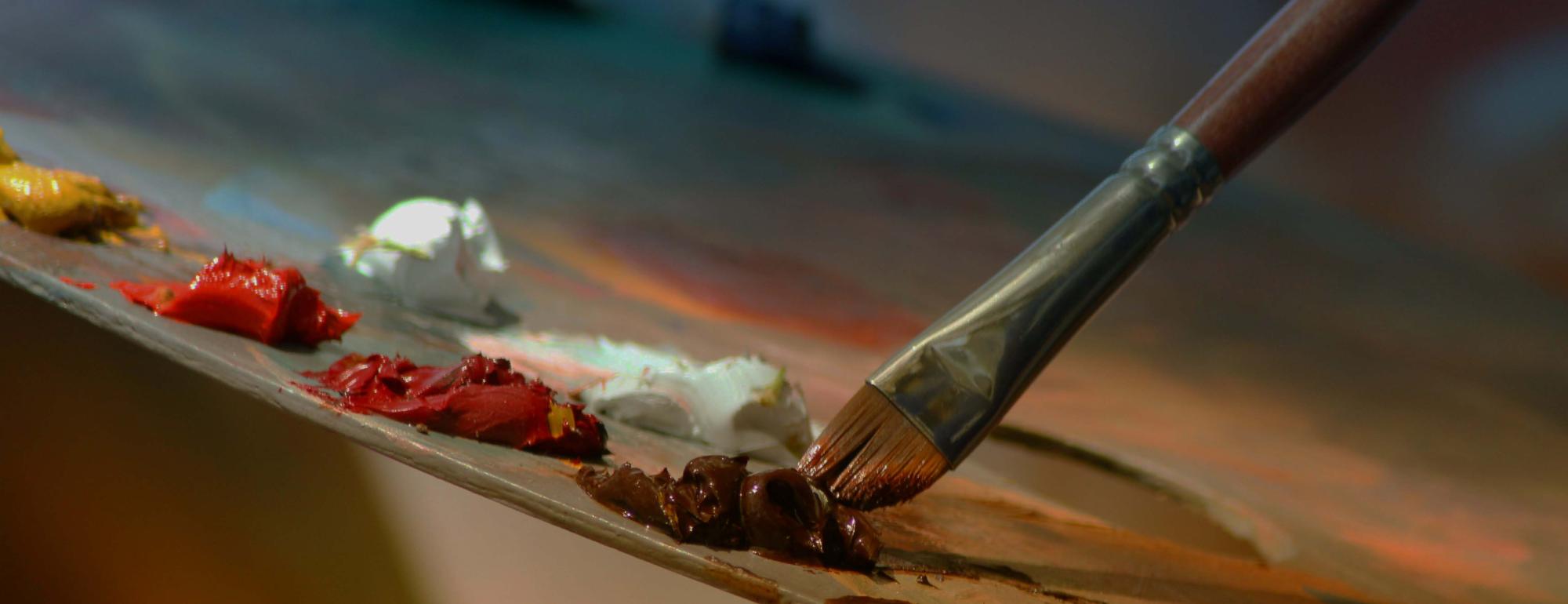 A zoomed in angle of a paintbrush swiping a paint pallete.